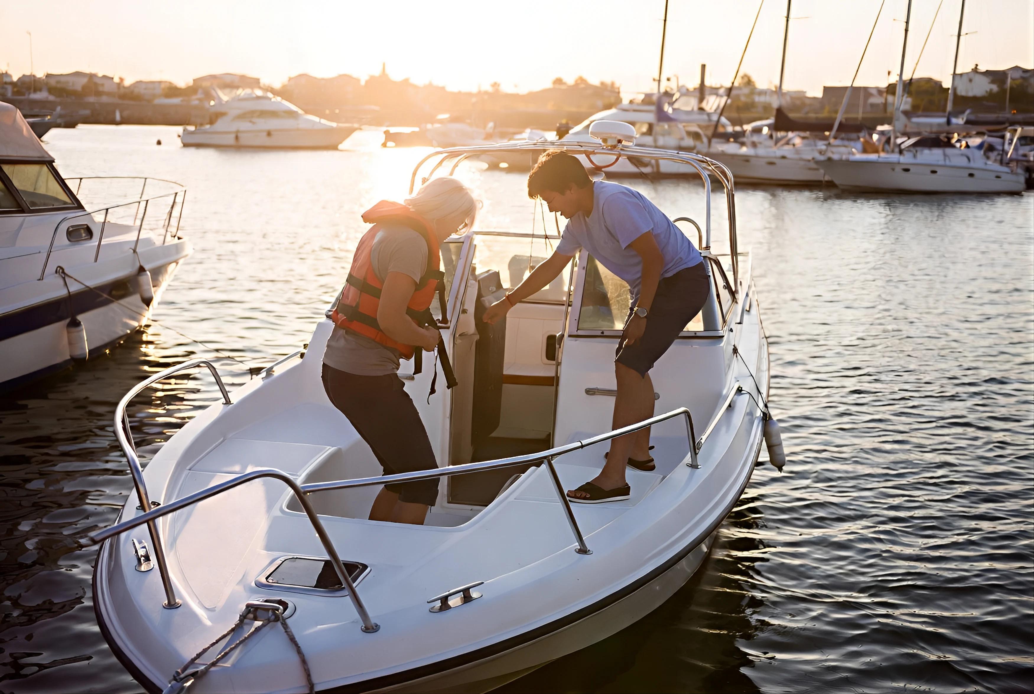 Two people checking a boat at a marina in warm evening light